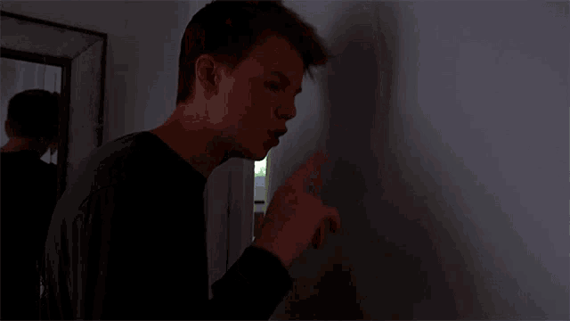 a man in a black shirt is standing in a dark room
