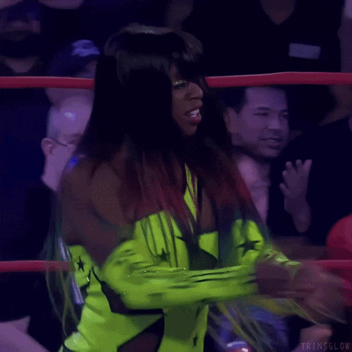 a female wrestler in a ring with the letters trnsglow on her arm