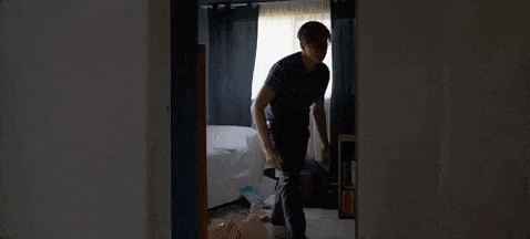 a man is standing in a bedroom looking out of a door .