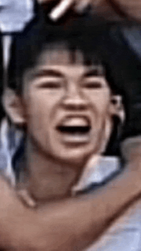 a close up of a man making a funny face with his mouth open in a crowd .