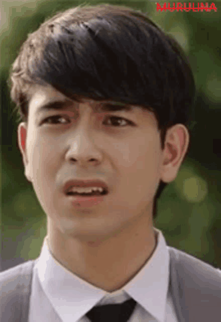a young man is wearing a white shirt and tie and making a funny face .