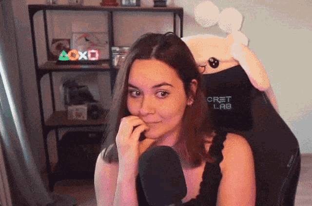 a woman sitting in front of a microphone with a stuffed animal behind her that says cret lab on it