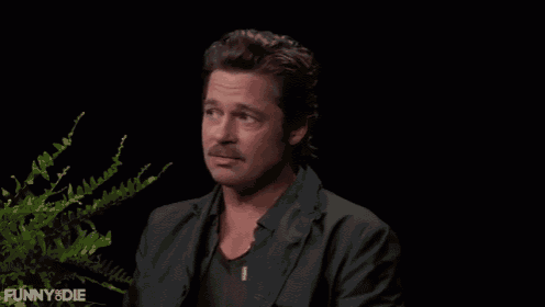 a man with a mustache is sitting in front of a plant and the words funny & die are on the bottom