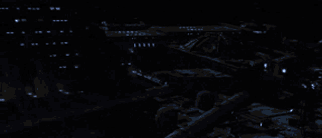 a plane is flying through the air in the dark with a blue light behind it .