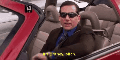 a man wearing sunglasses is sitting in a red car and says it 's britney bitch
