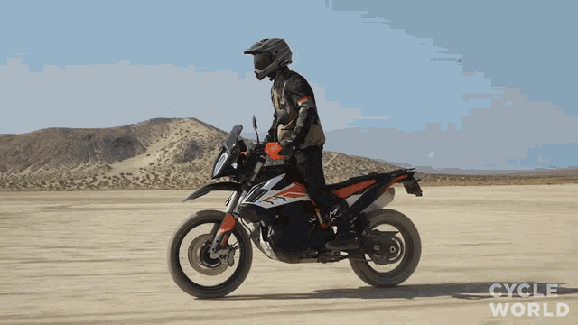 a man is riding a dirt bike in the desert with the words cycle world visible in the background