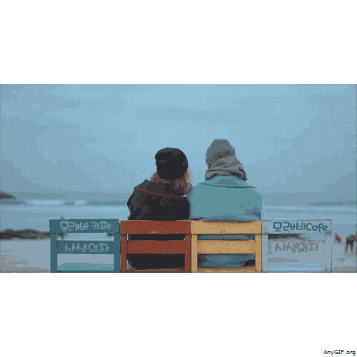 two people are sitting on a bench with a sign that says bicafe