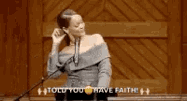 a woman is standing in front of a microphone and saying `` told you have faith ! ''