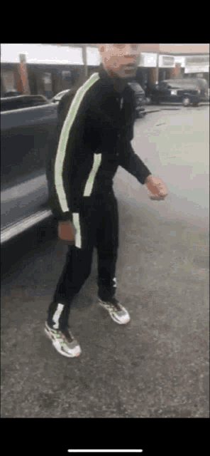 a man wearing a black jacket with neon green stripes on the side is walking down the street .