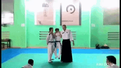a group of people are standing on a karate mat .