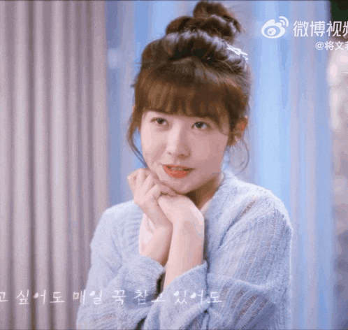 a woman in a blue sweater has a bun on her hair