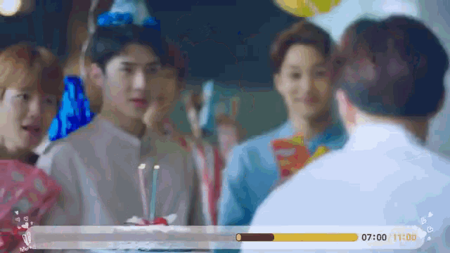 a group of people standing around a cake with candles on it .