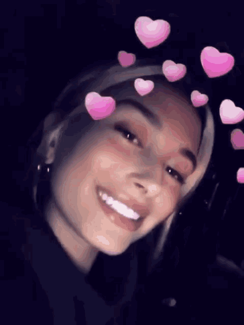 a close up of a woman 's face with pink hearts in her hair