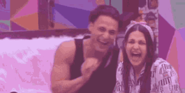 a man and a woman are sitting next to each other laughing .