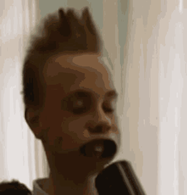 a young boy with a mohawk is brushing his teeth with a black mouth guard .