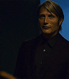 a man wearing a black suit and black shirt is looking at the camera