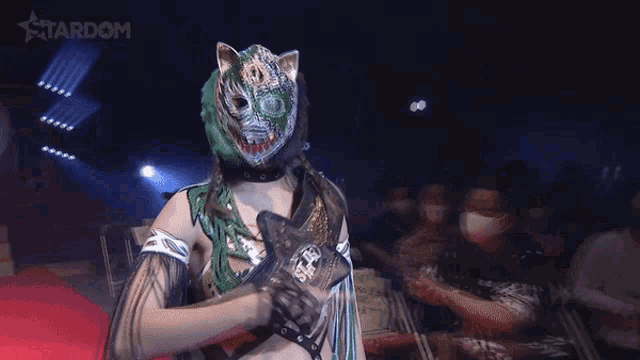 a woman in a tiger mask is standing on a red carpet in front of a stardom logo