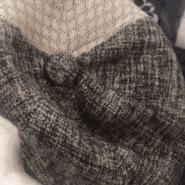 a close up of a gray and white sweater with a knot in the middle