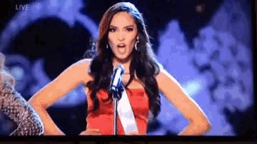 a woman in a red dress is singing into a microphone on a stage .