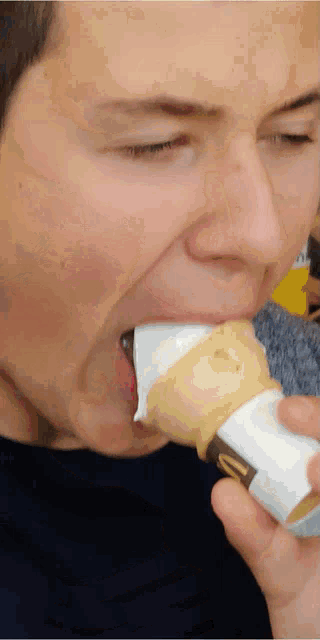 a close up of a man eating an ice cream cone with the letter m on it