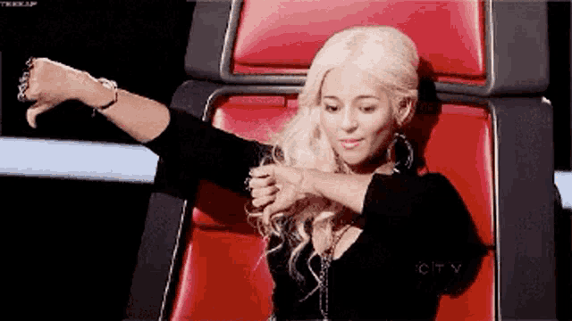 a woman with blonde hair is sitting in a red chair