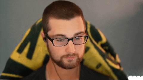 a man with glasses and a beard is sitting in front of a yellow and green flag