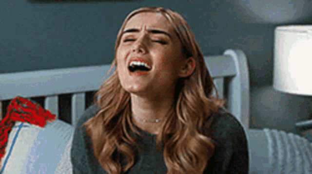 a woman is sitting on a bed with her eyes closed and her mouth open .