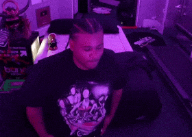 a man in a purple shirt is sitting in a room