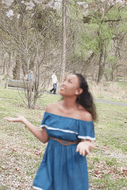 a woman in a blue off the shoulder dress throws petals in the air