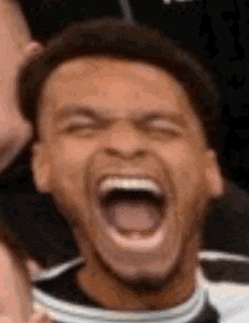 a man is laughing with his mouth wide open and his eyes closed .