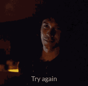 a man in a dark room is smiling and saying try again
