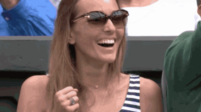 a woman wearing sunglasses and a striped tank top smiles