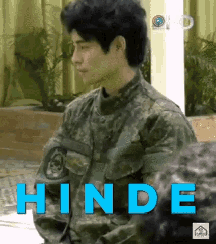 a man in a military uniform is sitting in front of a sign that says hinde