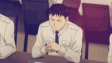 a man in a white shirt and tie sits at a table with his hands folded .