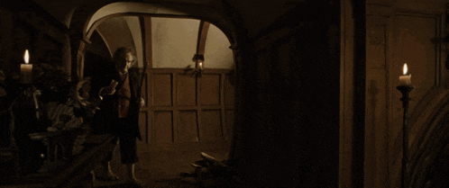 a man holding a book in a dark room with a fireplace