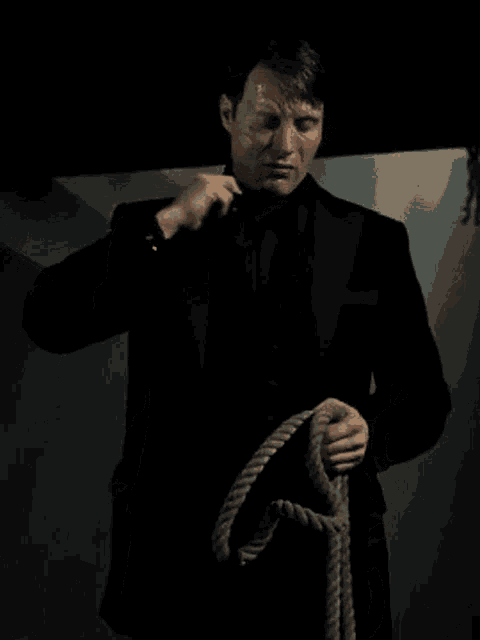 a man in a tuxedo is tying a rope