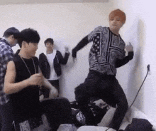 a group of young men are dancing in a room and one of them is jumping in the air .