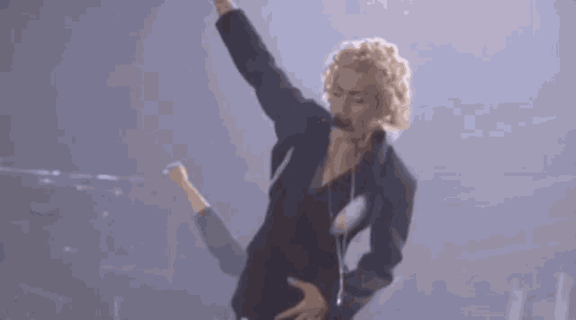 a woman is dancing on a stage with her arms in the air and a microphone in her hand .