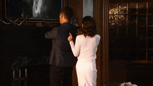 a man in a suit and a woman in a white skirt are standing next to each other