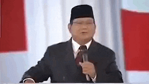 a man in a suit and tie is talking into a microphone .