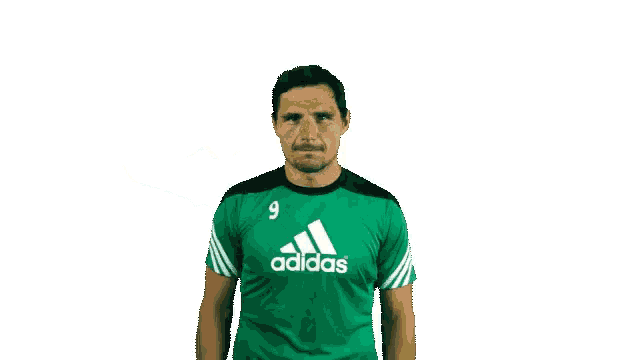 a man in a green adidas shirt giving a thumbs down