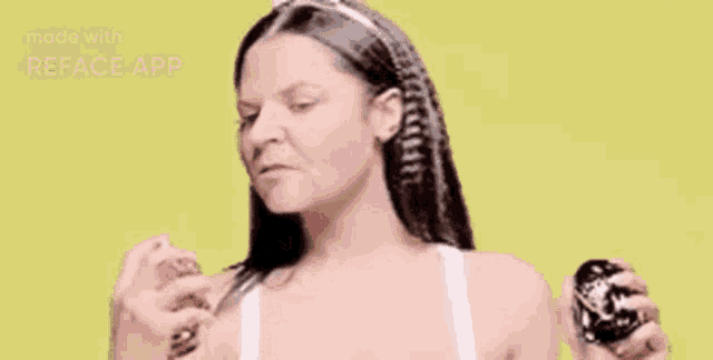 a woman is holding a bottle of perfume and spraying it on her face .