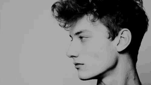 a black and white photo of a man 's face with curly hair