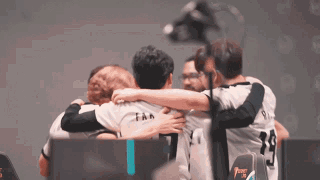 a group of men hugging each other with one wearing a shirt that says fan on it