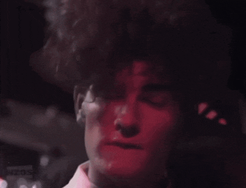 a close up of a person 's face with a red light behind him .
