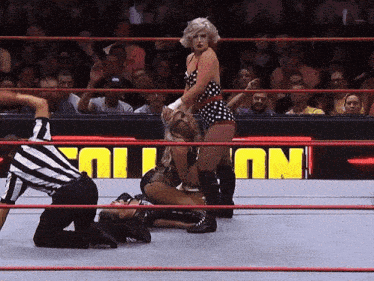 a woman in a polka dot dress is kneeling down in a wrestling ring in front of a sign that says " no "