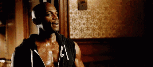 a man is standing in a dark room wearing a black hoodie without a shirt on .