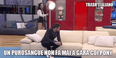 a man is sitting on a couch in a living room with a woman standing behind him and a caption that says trash italiano