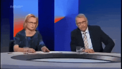 a man and a woman are sitting at a table in front of a screen that says news