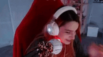 a woman is sitting in a red chair wearing headphones and a santa hat .